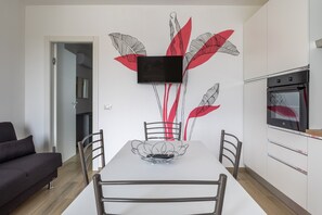 Une cuisine moderne équipée d’un téléviseur à écran plat fixé au-dessus d’une table à manger, d’un canapé et d’un plan de travail avec un four.