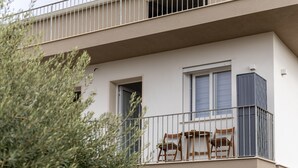 Un edificio de varios pisos con un balcón que tiene dos sillas de madera y una mesita.