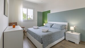 A bedroom with a bed, bedside tables, a desk, and a window.
