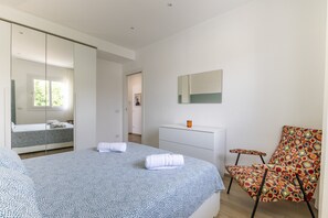 Une chambre à coucher avec un lit, une chaise, une commode et un miroir.