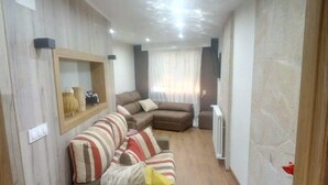 Un salón con un sofá modular, una mesita con adornos y un espejo en la pared.