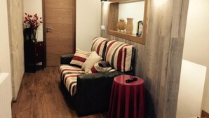 Una habitación acogedora con sofá, una mesita, un espejo y una puerta.