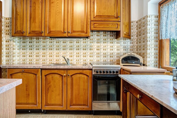 A kitchen with wooden cabinets, a stove, and a toaster.