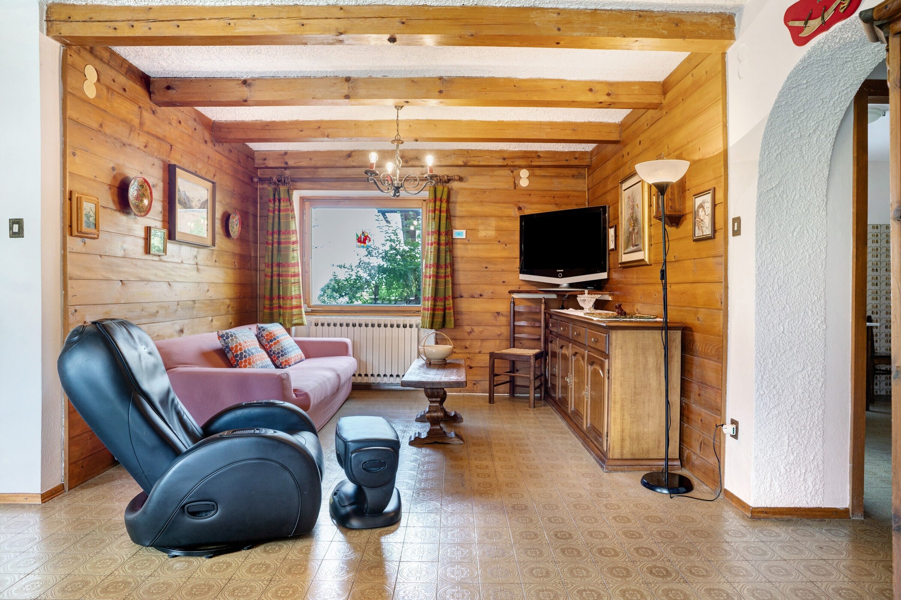 Un interior de madera con sofá, sillón de masaje, televisor y zona de comedor.