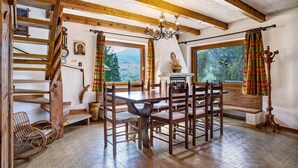 Una mesa de comedor de madera con sillas, una araña y vistas al exterior.