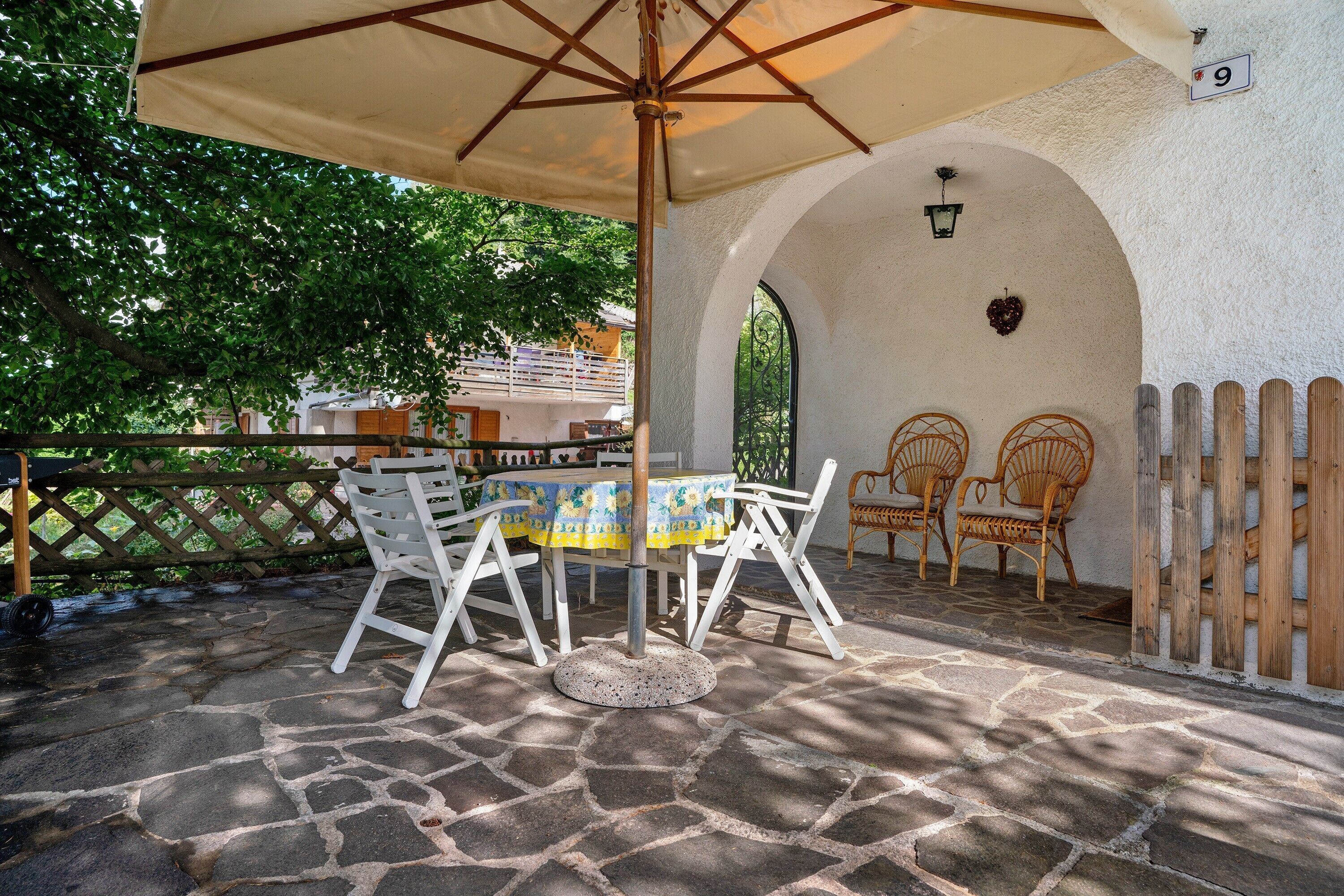 Eine Terrassengruppe im Freien mit Tisch und Stühlen, einem Holzzaun und einem Steinboden.