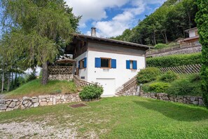 A white building with blue shutters, a stone staircase, and a stone wall.