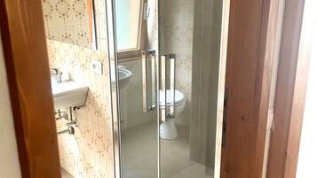 Een badkamer met toilet, douche en wastafel.