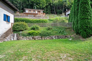 A residential property with a stone wall, a wooden fence, and a large coniferous tree.