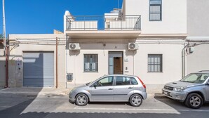 A two-story building with a balcony, a garage door, and two parked cars.