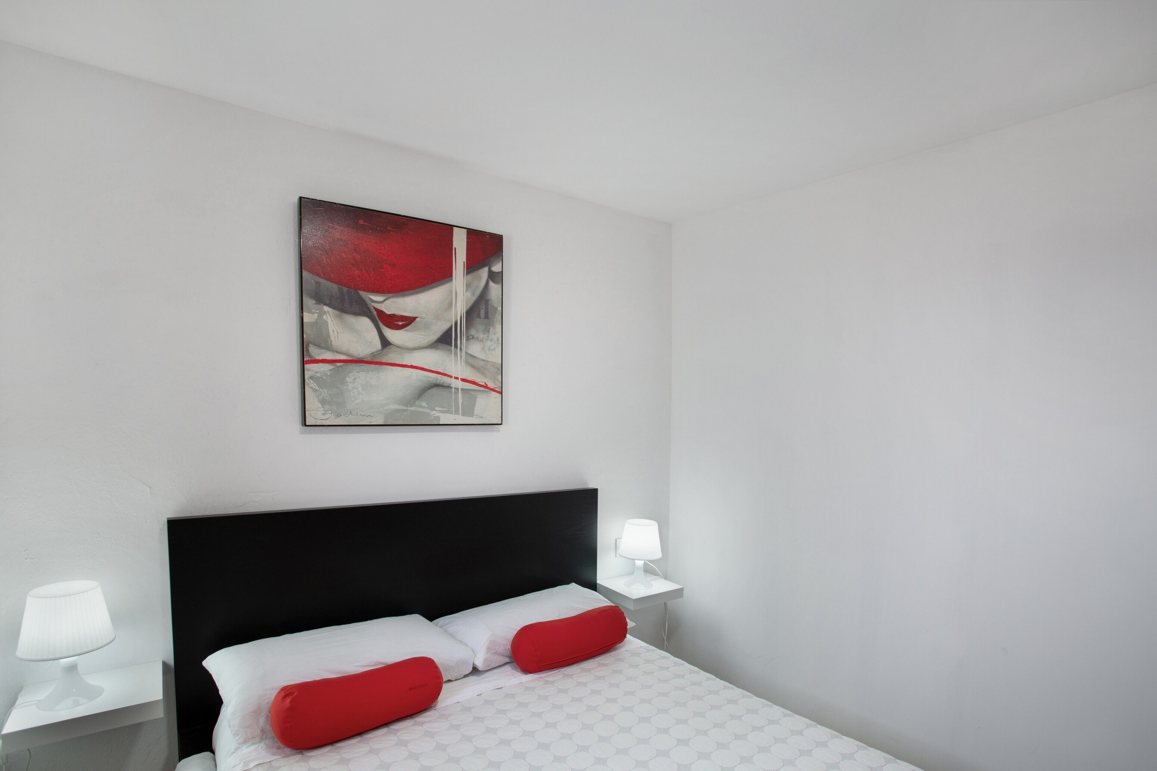 Una habitación de hotel con una cama, una mesita de noche, una lámpara y un cuadro en la pared.