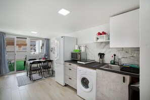 A compact kitchen with a washing machine, microwave, and a small sink.
