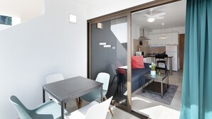 A modern apartment with a dining area, a sofa, a kitchen, and a sliding glass door. - Vacation Home 'Casa Neale' with Sea View, Shared Pool and Private Terrace (Puerto Rico)