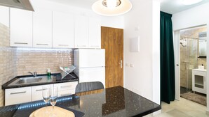 A modern kitchen with white cabinets, a black countertop, and a wooden door. - Vacation Home 'Casa Neale' with Sea View, Shared Pool and Private Terrace (Puerto Rico)