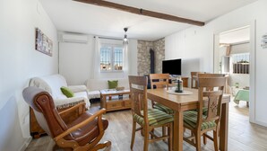 Ein Wohnzimmer mit einer Couch, einem Holzesstisch, Stühlen, einem Fernseher und einer Steinwand.