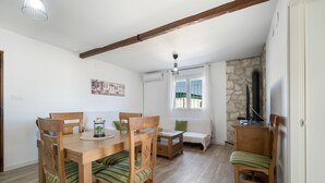 Ein Essbereich mit Holztisch und -stühlen, einer Couch, einer Steinwand und einem Fernseher.
