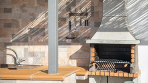 Ein Backstein-Grill, eine Spüle und ein an der Wand befestigter Küchenutensilienhalter.