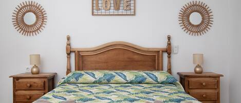 Une chambre à coucher avec un lit en bois, deux tables de chevet, un élément décoratif mural et une lampe de chevet.