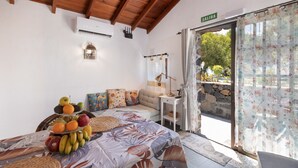 A bedroom with a bed, a fruit display, a lamp, a small table, and a view of the outdoors.