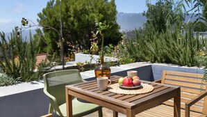 A wooden table with a woven placemat, a bottle, and a plate of fruit.