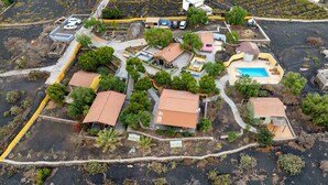 An aerial view of a residential area with houses, a swimming pool, and a small garden area.