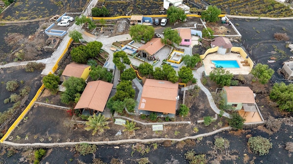An aerial view of a residential area with houses, a swimming pool, and a small garden area.
