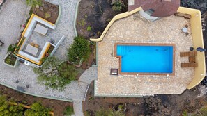 An aerial view of a property with a swimming pool, outdoor seating, and a garden area.