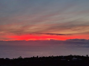A coastal sunset with a silhouette of a town below.