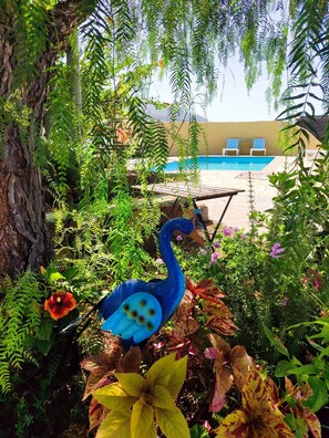 A pool area with lounge chairs and a decorative bird sculpture amidst lush greenery.
