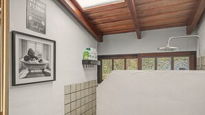 Ein Badezimmer mit Dusche, einem gerahmten Foto an der Wand und einem Ablagefach für Toilettenartikel.