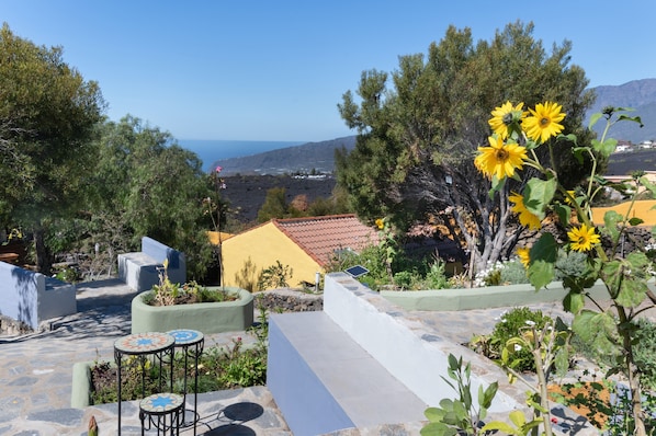 A rooftop garden with outdoor seating, a view of the sea, and surrounding vegetation.