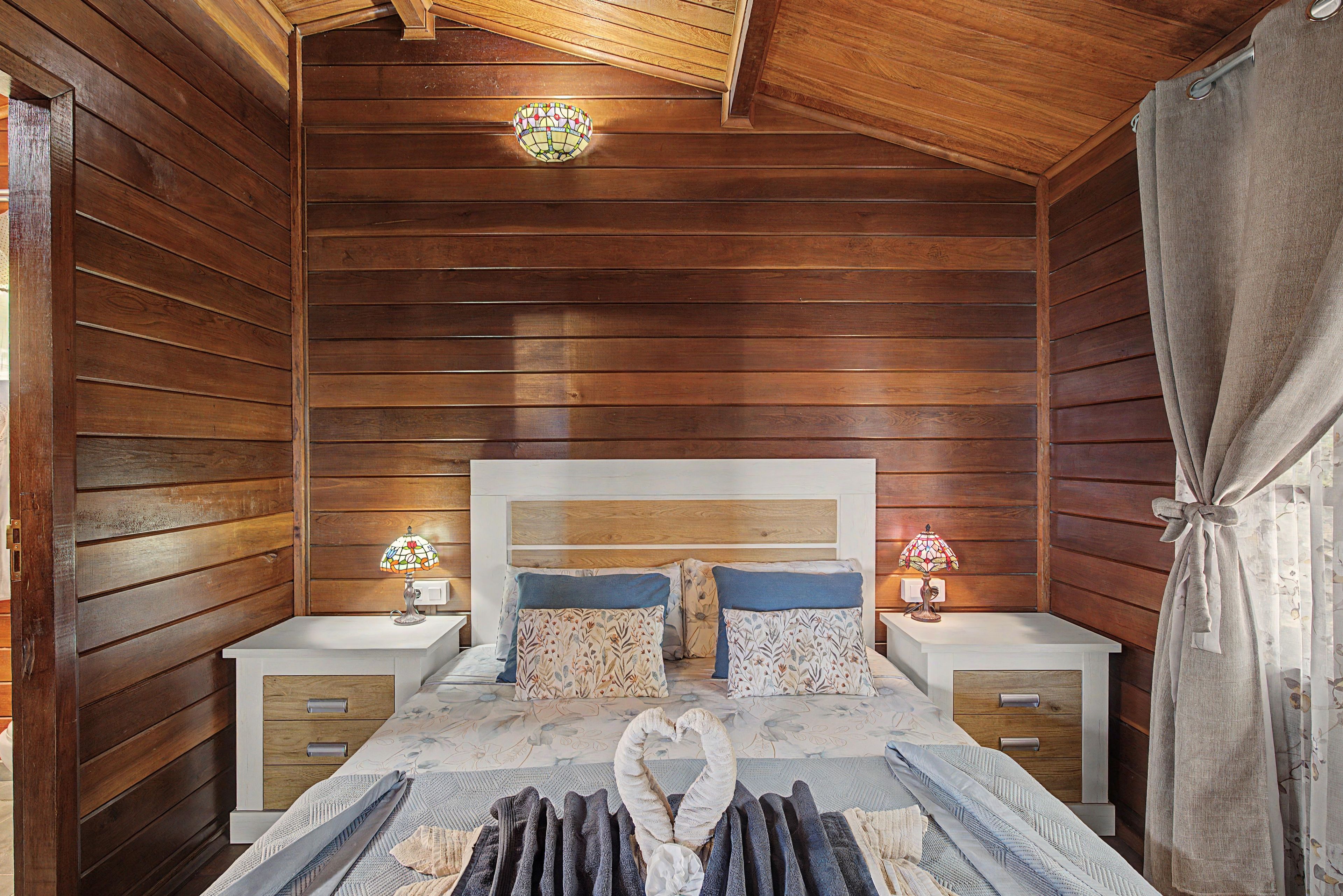 Een kamer met houten vloeren, een bed, twee nachtkastjes en een kroonluchter.