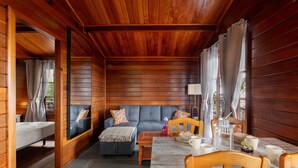 A wooden cabin interior with a sofa, dining table, and chairs.