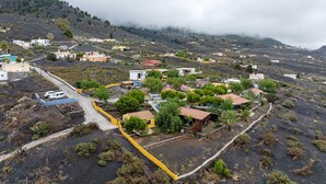 A hillside village with houses, a road, and a yellow fence. - Holiday Home 'La Cabaña Del Atardecer' with Sea View, Wi-Fi and Air Conditioning (Los Llanos de Aridane)