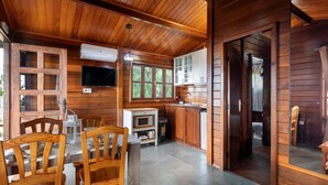 A wooden cabin interior with a dining area, kitchen, and a television.