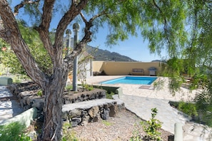 A pool area with stone steps, a tree, and a building in the background. - Holiday Home 'La Cabaña Del Atardecer' with Sea View, Wi-Fi and Air Conditioning (Los Llanos de Aridane)