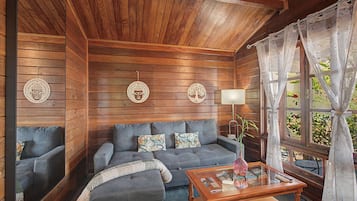Ein Zimmer mit Holzwänden, einer Couch, einem Glastisch und Wanddekorationen.