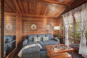 A wooden-paneled room with a sofa, a glass coffee table, and decorative wall art.