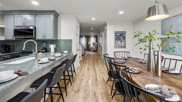A modern kitchen with a marble countertop, stainless steel appliances, and a dining area with a wooden table and chairs.
