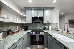 Enjoy cooking in this well-equipped kitchen with a range hood, oven, and granite countertop.