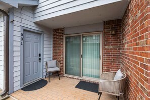 Welcome to an entrance with a cozy porch area featuring a wicker chair and bench.