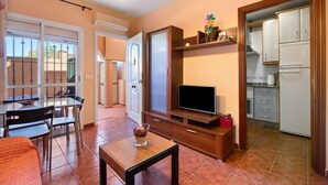 A compact living space with a dining area, a TV, and a kitchen.