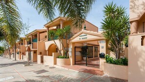 A hotel entrance with a gated driveway, palm trees, and a sign indicating the name 'RESORT ANDALUS.'