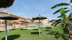 A courtyard with thatched umbrellas, a central fountain, and a pool.