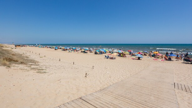 A beach with a wooden boardwalk, umbrellas, and people. - Holiday Home 'Casa Fran' with Sea View, Shared Pool and Air Conditioning (Oliva)