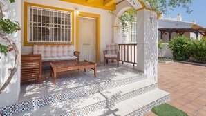 A covered patio with a wooden bench, two chairs, and a small table. - Holiday Home 'Casa Fran' with Sea View, Shared Pool and Air Conditioning (Oliva)