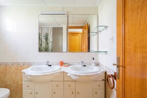Un baño con dos lavabos, un espejo y una puerta de madera.