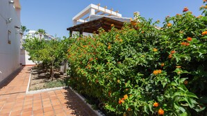 A courtyard with a tiled pathway, a pergola, and flowering plants. - Holiday Home 'Casa Fran' with Sea View, Shared Pool and Air Conditioning (Oliva)