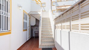 A narrow corridor with a tiled floor, a staircase with patterned tiles, and a white wall with a yellow trim. - Holiday Home 'Casa Fran' with Sea View, Shared Pool and Air Conditioning (Oliva)
