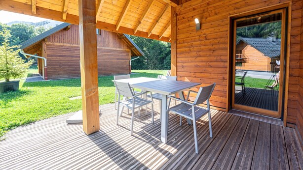 Una cabaña de madera con un balcón, una mesa y sillas.